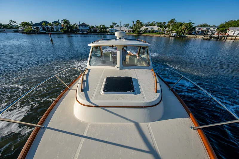 Slide: The Image of 2016 Hinckley Talaria 34 cruising on a serene waterway with waterfront homes in the background. - 27