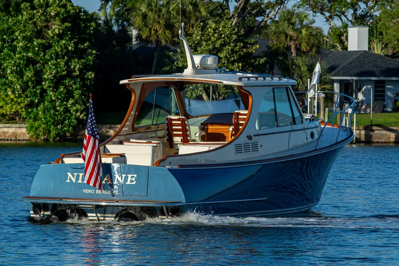 Slide: The Image of 2016 Hinckley Talaria 34 cruising on a serene waterway, displaying an American flag. - 3