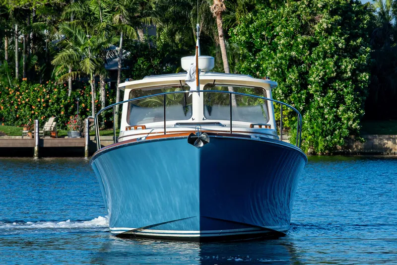 Slide: The Image of 2016 Hinckley Talaria 34 boat on water, surrounded by lush greenery. - 5