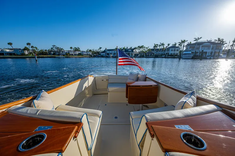 Slide: The Image of 2016 Hinckley Talaria 34 boat with elegant seating, American flag, and scenic waterfront view. - 9