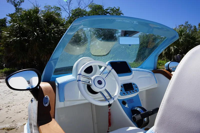 Slide: The Image of 2025 Car Off-shore Fiat 500 Classic interior with blue accents, parked on a sandy beach. - 9