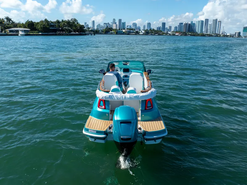 Slide: The Image of Aqua blue Car Off-shore Fiat 500 Classic boat on water, city skyline in background. - 11