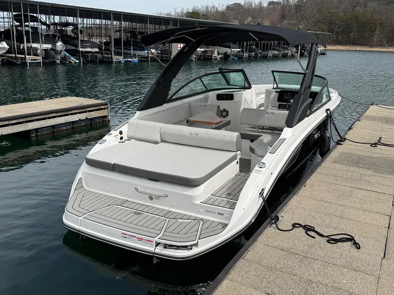 Slide: The Image of 2025 Sea Ray SDX 250 boat docked on calm water, featuring sleek design and spacious seating. - 2