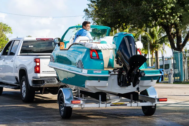 Slide: The Image of A Fiat 500 Classic boat on a trailer, towed by a white truck. - 10