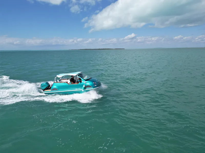 Slide: The Image of Amphibious vehicle resembling a Fiat 500 Classic navigating turquoise waters under a clear sky. - 7