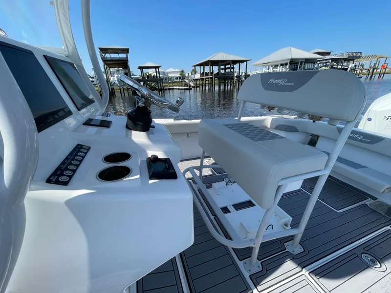 Slide: The Image of 2023 Front Runner 26 Center Console boat interior with helm and seating, docked by waterfront. - 22