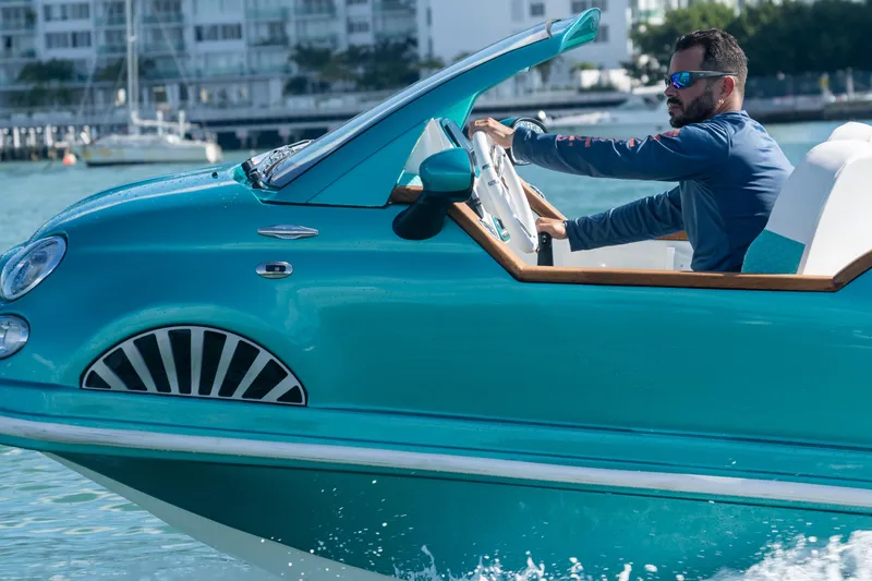 Slide: The Image of Man driving a 2025 Car Off-shore Fiat 500 Classic on water. - 2
