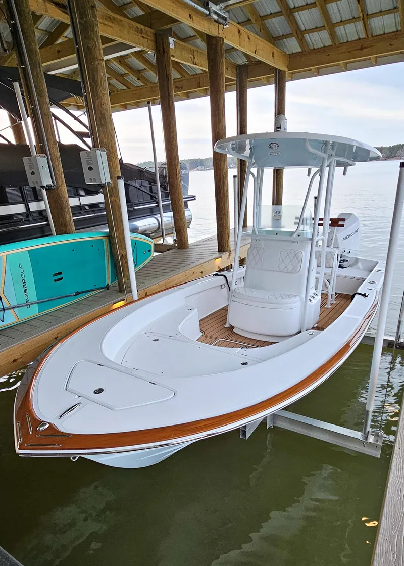 Slide: The Image of 2025 Chaos 21 Tarpon Bay boat docked under a wooden shelter. - 10