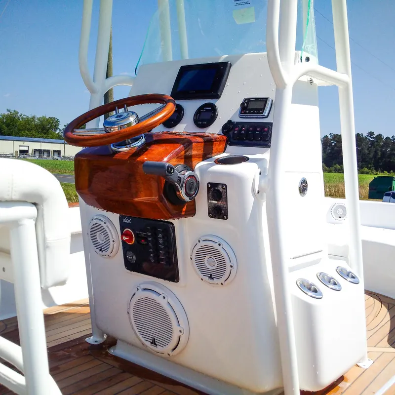 Slide: The Image of 2025 Chaos 21 Tarpon Bay boat console with wooden steering wheel and modern controls. - 12