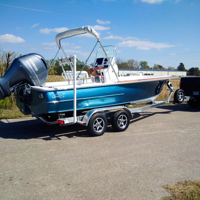 Slide: The Image of 2025 Chaos 21 Tarpon Bay boat on trailer, parked outdoors under clear sky. - 3