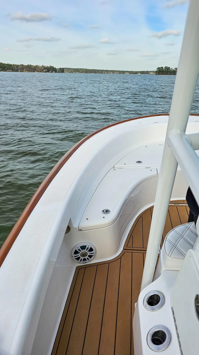 Slide: The Image of 2025 Chaos 21 Tarpon Bay boat on calm water, featuring sleek design and wooden deck. - 7