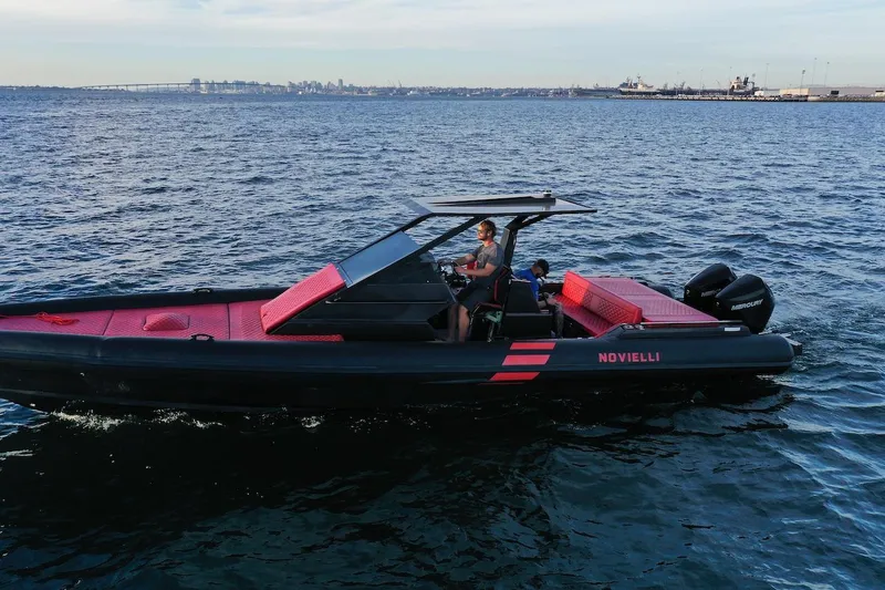 Slide: The Image of 2023 Novielli Veloche 349 boat cruising on open water with city skyline in background. - 15