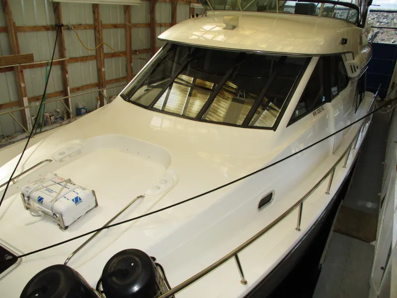 Slide: The Image of 2000 Bayliner 5288 Pilot House yacht in storage, showcasing sleek design and spacious deck. - 2