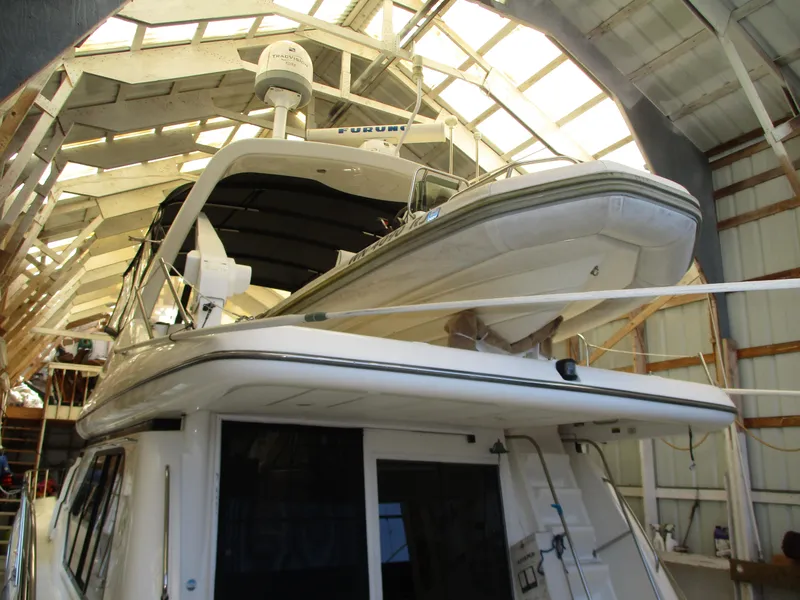 Slide: The Image of 2000 Bayliner 5288 Pilot House yacht in a boat shed, showcasing upper deck and radar equipment. - 20