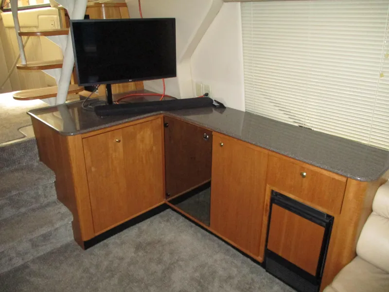 Slide: The Image of 2000 Bayliner 5288 Pilot House interior with TV, wooden cabinets, and carpeted flooring. - 39