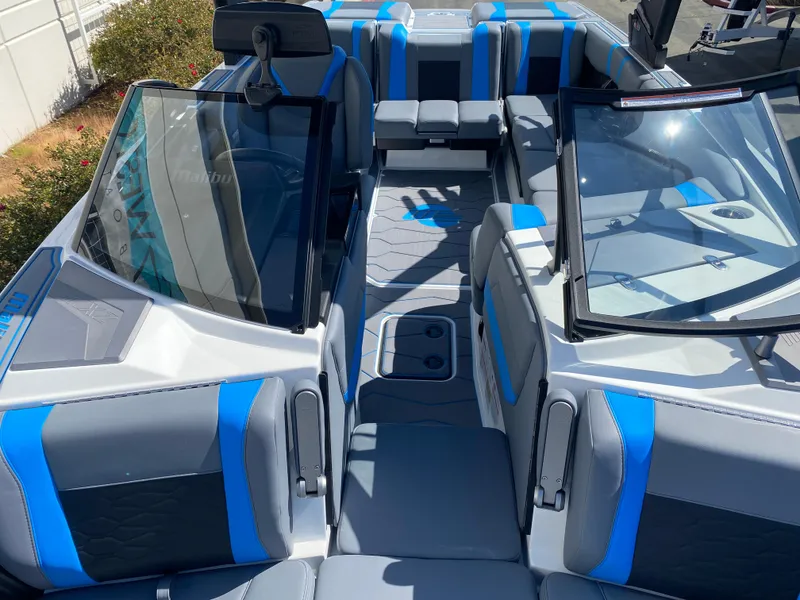 Slide: The Image of 2025 Malibu Wakesetter 23 MXZ interior with blue and gray seating, open bow design. - 10