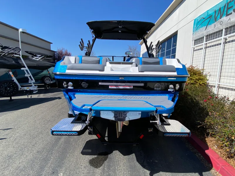 Slide: The Image of 2025 Malibu Wakesetter 23 MXZ boat, blue and white, parked outdoors. - 4