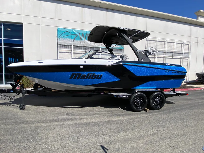 Slide: The Image of 2025 Malibu Wakesetter 23 MXZ boat in blue and black on a trailer. - 7