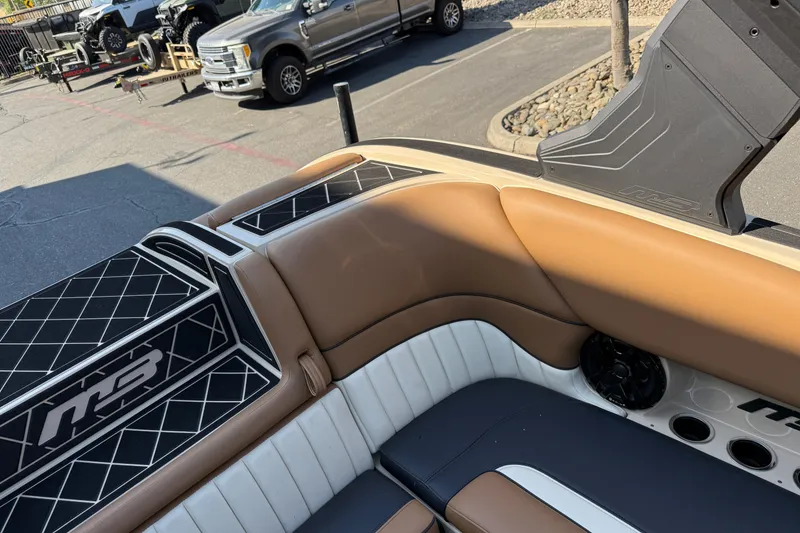 Slide: The Image of 2025 MB B52 21 Alpha boat interior with tan and black seating, parked outdoors. - 20