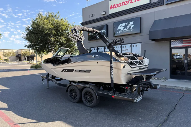 Slide: The Image of 2025 MB B52 21 Alpha boat on trailer outside dealership, sunny day. - 5