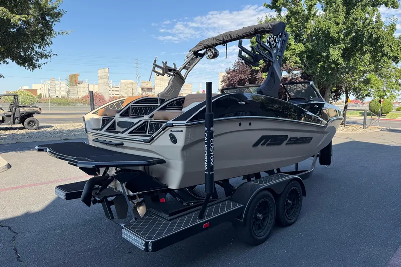 Slide: The Image of 2025 MB B52 21 Alpha boat on trailer, parked outdoors, showcasing sleek design and modern features. - 7