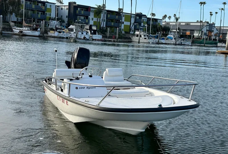 Slide: The Image of 2008 Boston Whaler 130 Sport boat on calm water near a marina. - 0