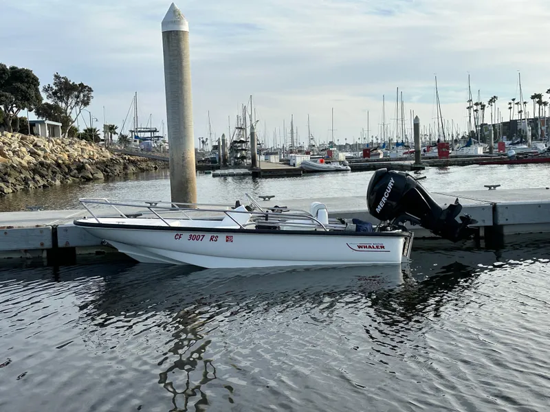 Slide: The Image of 2008 Boston Whaler 130 Sport docked in a marina with sailboats in the background. - 1