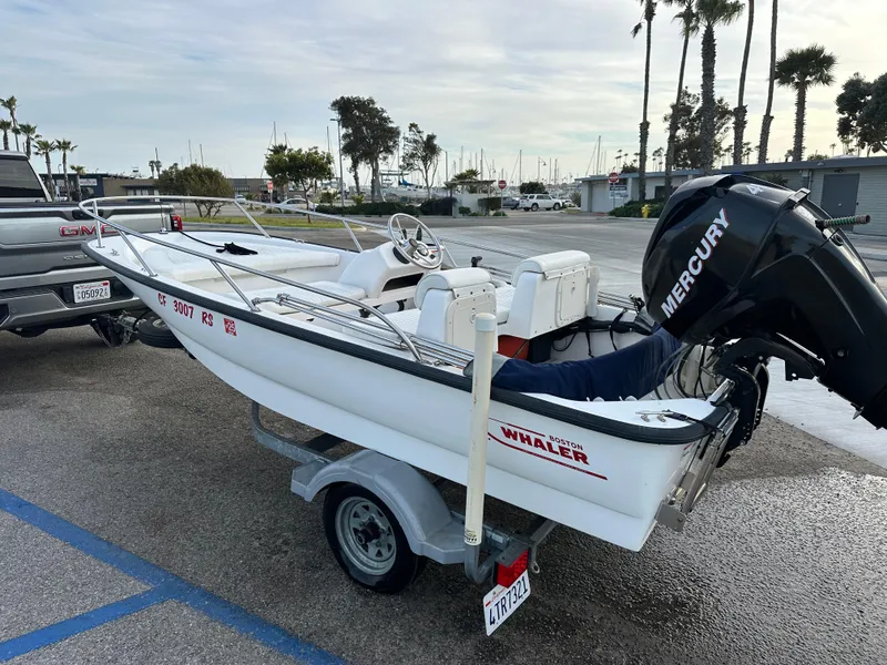 Slide: The Image of 2008 Boston Whaler 130 Sport boat on trailer with Mercury engine, parked near marina. - 5