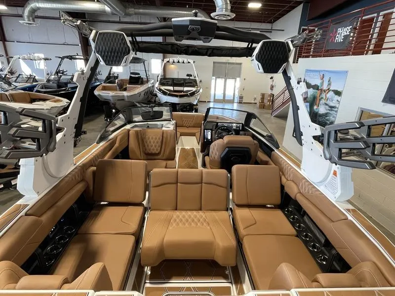 Slide: The Image of Luxurious interior of 2025 Malibu M230 boat with tan leather seating in showroom. - 11