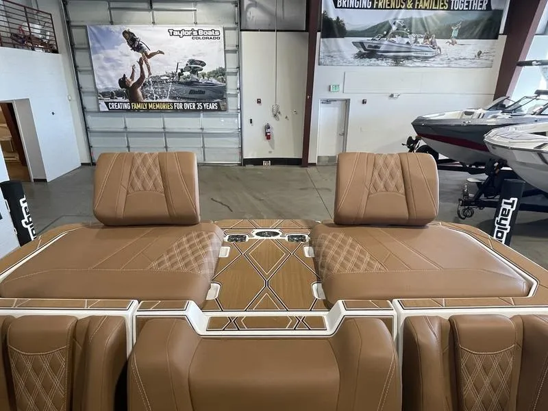 Slide: The Image of 2025 Malibu M230 boat interior with tan leather seats in showroom. - 28