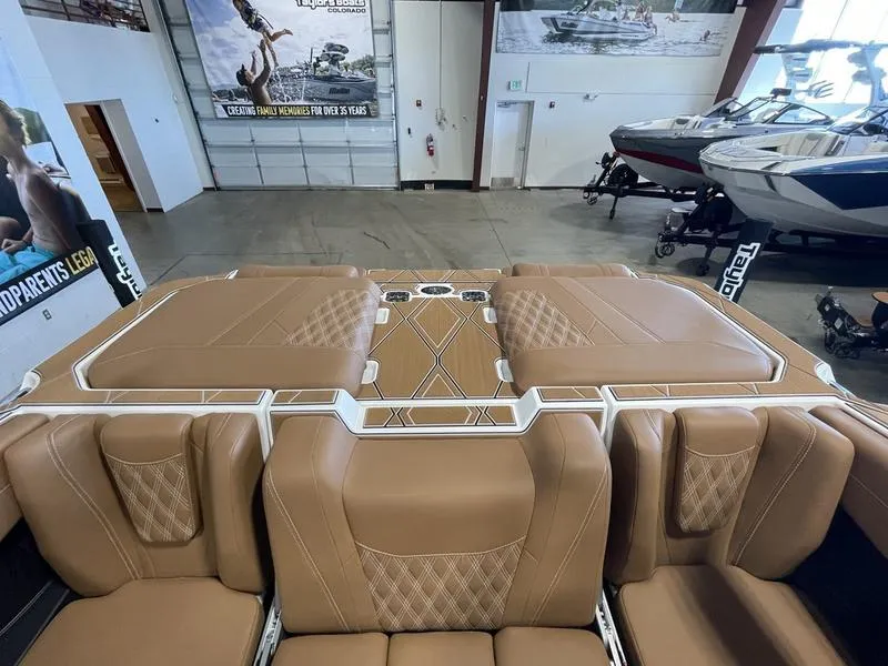 Slide: The Image of 2025 Malibu M230 boat interior with tan leather seating in showroom. - 29