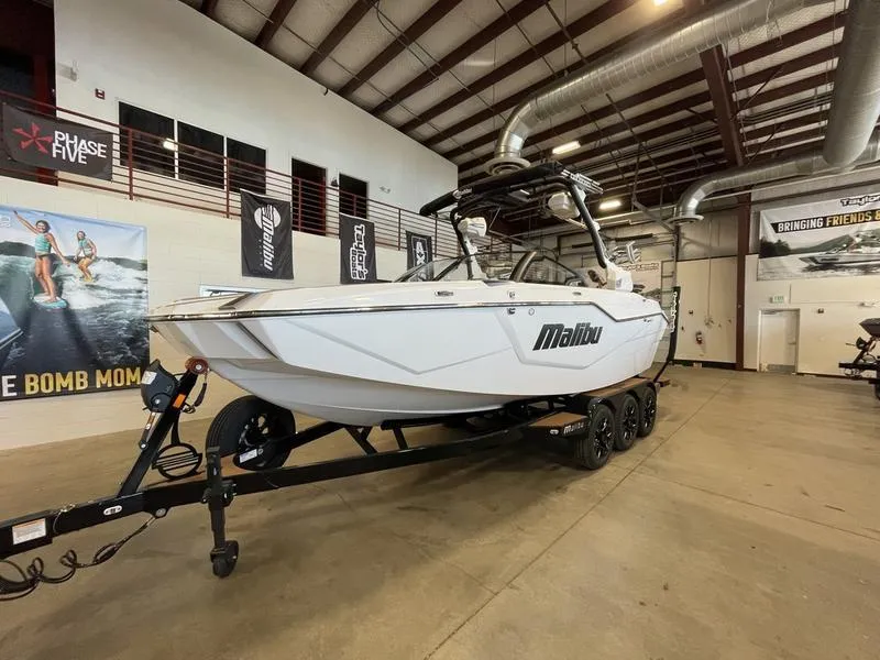 Slide: The Image of 2025 Malibu M230 boat on trailer in showroom, featuring sleek design and modern features. - 3