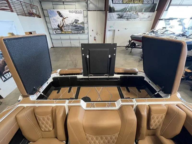 Slide: The Image of 2025 Malibu M230 boat interior with tan leather seats and open storage compartments. - 30