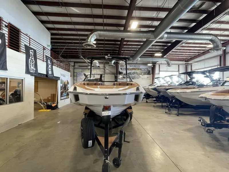 Slide: The Image of 2025 Malibu M230 boat displayed in a showroom with industrial ceiling. - 4