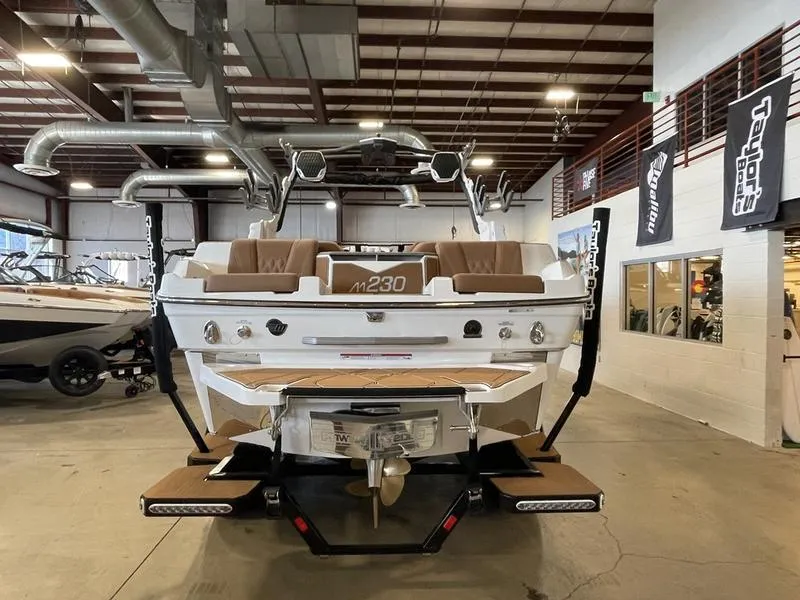 Slide: The Image of 2025 Malibu M230 boat in showroom, rear view, showcasing sleek design and modern features. - 8