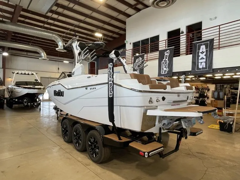Slide: The Image of 2025 Malibu M230 boat on trailer in showroom, featuring sleek design and modern amenities. - 9