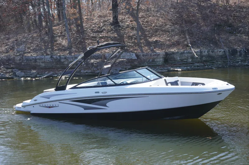 The Image of 2025 Monterey M22 boat on calm water near a wooded shoreline. - 0
