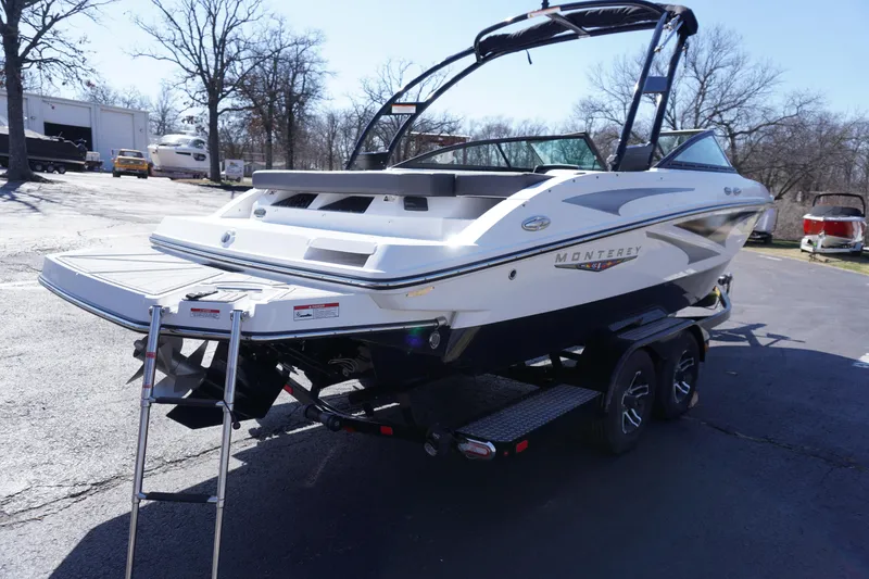 Slide: The Image of 2025 Monterey M22 boat on trailer, parked outdoors, rear view with swim platform and ladder. - 8