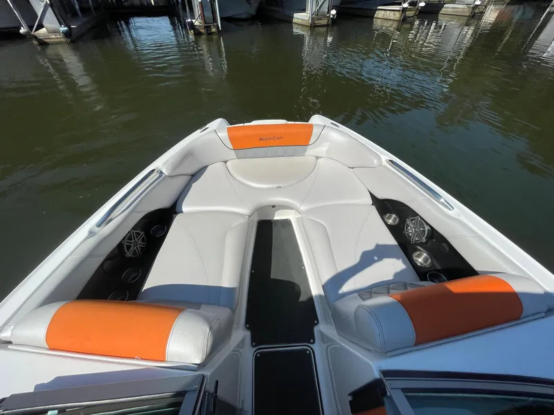 Slide: The Image of 2012 MasterCraft X45 boat interior with orange and white seating, docked on calm water. - 6