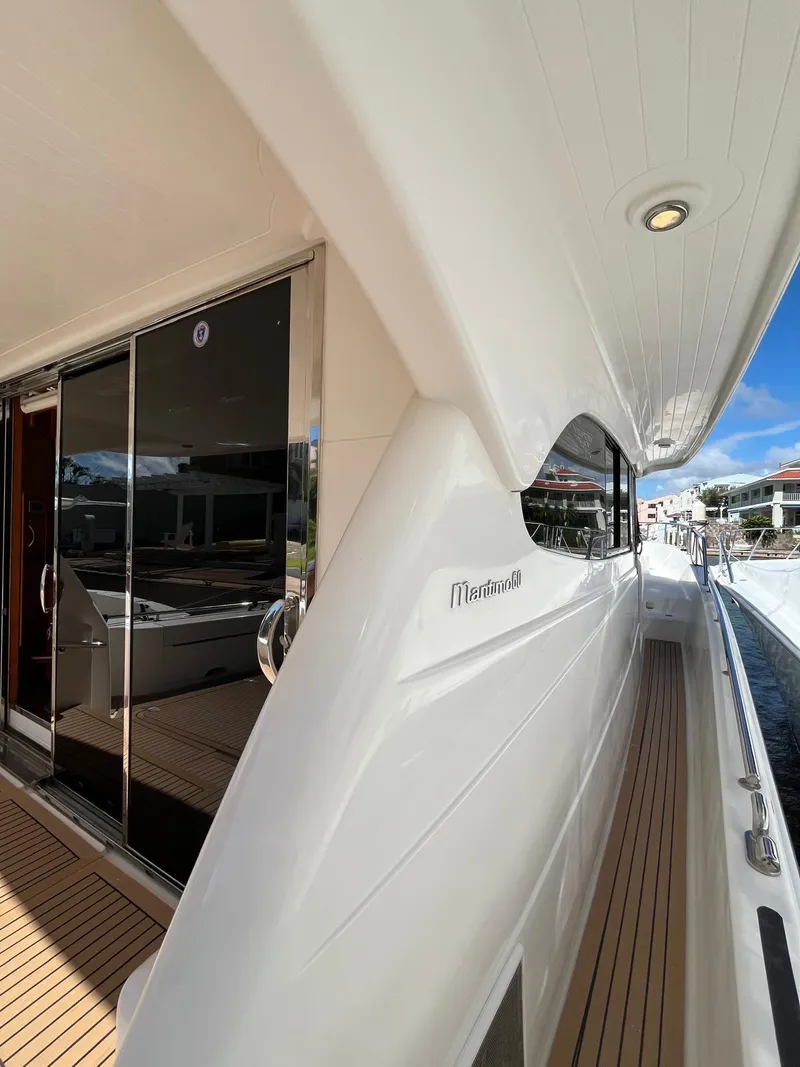 Slide: The Image of 2007 Maritimo M60 yacht with sleek white exterior and wooden deck, docked at a marina. - 4
