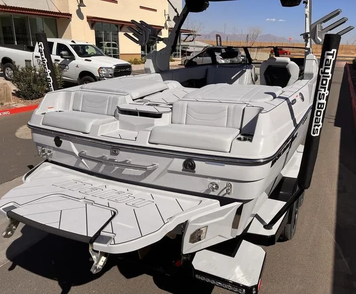 Slide: The Image of 2025 Malibu 23 LSV boat with sleek design and spacious seating, parked outdoors. - 10