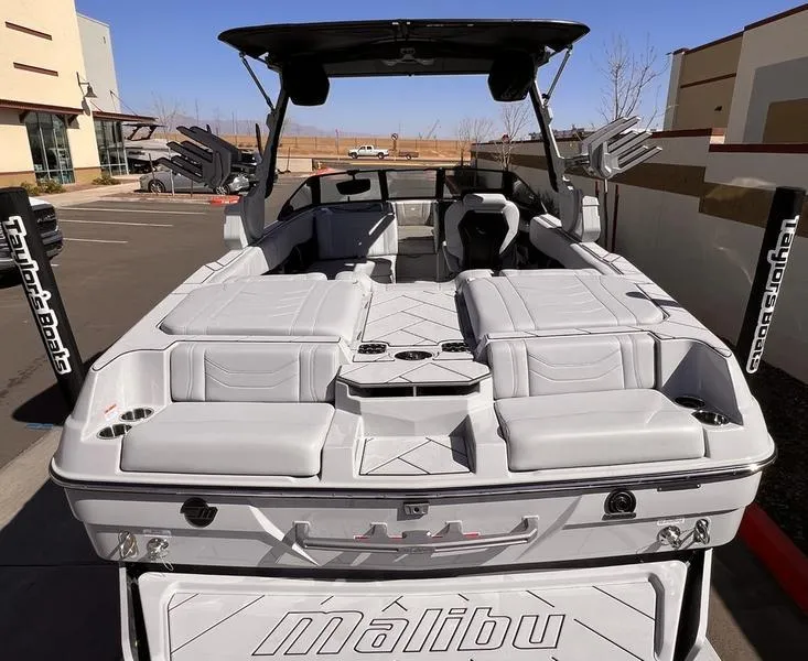 Slide: The Image of 2025 Malibu 23 LSV boat with sleek design and spacious seating in a parking lot. - 11