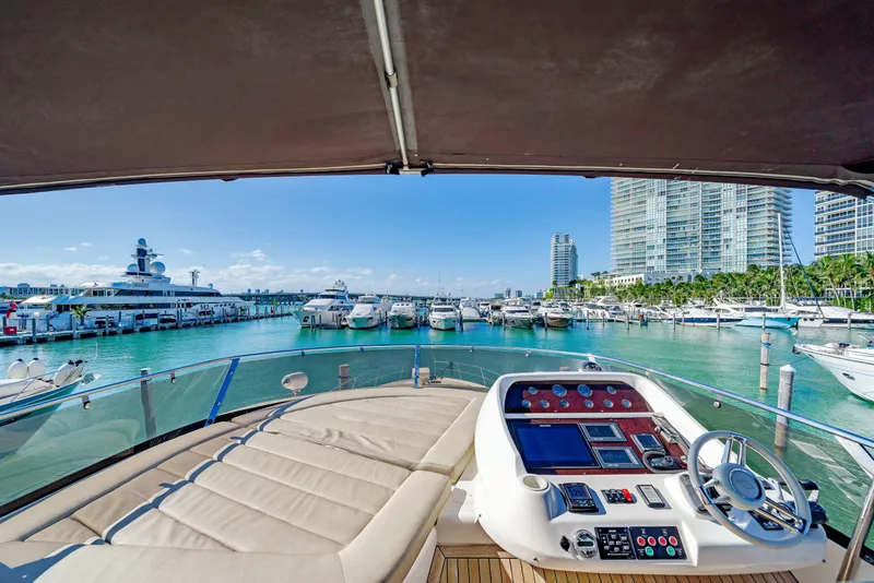 Slide: The Image of Sunseeker Manhattan 70 yacht helm view, overlooking marina with luxury boats and city skyline, 2009 model. - 38