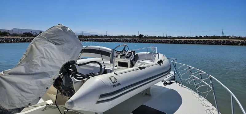 Slide: The Image of 1995 Bertram Convertible boat with inflatable dinghy on deck, docked in a calm marina. - 11