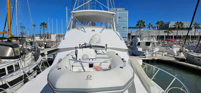 Slide: The Image of 1995 Bertram Convertible yacht docked at marina, featuring inflatable boat on deck. - 12