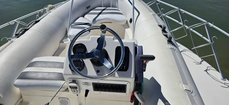 Slide: The Image of 1995 Bertram Convertible boat interior with steering wheel and seating, on calm water. - 13