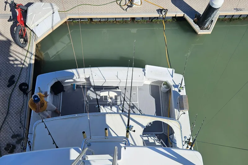 Slide: The Image of 1995 Bertram Convertible boat docked, viewed from above, with fishing rods and a bicycle nearby. - 20
