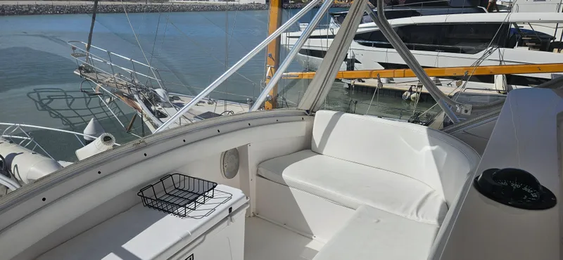 Slide: The Image of 1995 Bertram Convertible yacht interior with white seating, docked at marina. - 25