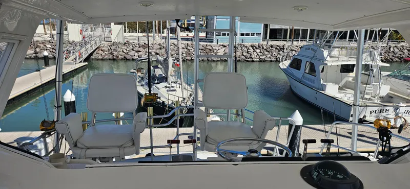 Slide: The Image of 1995 Bertram Convertible yacht interior with white seating, docked in a marina. - 26