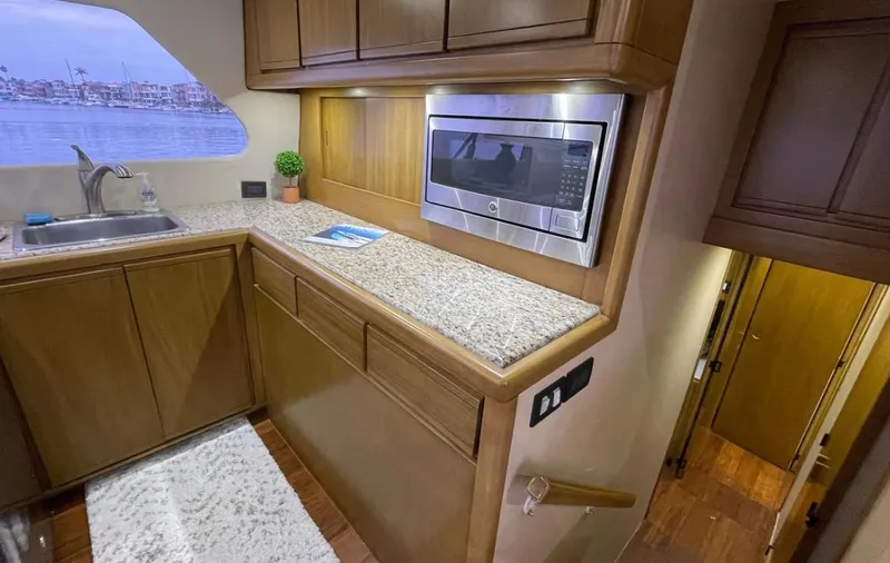 Slide: The Image of 1995 Bertram Convertible yacht kitchen with granite countertops, microwave, and sink, overlooking marina view. - 34